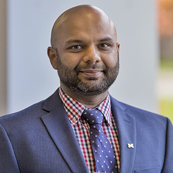 Professional headshot of assistant research scientist, Avin Vijay, standing and smiling in a suit and tie.